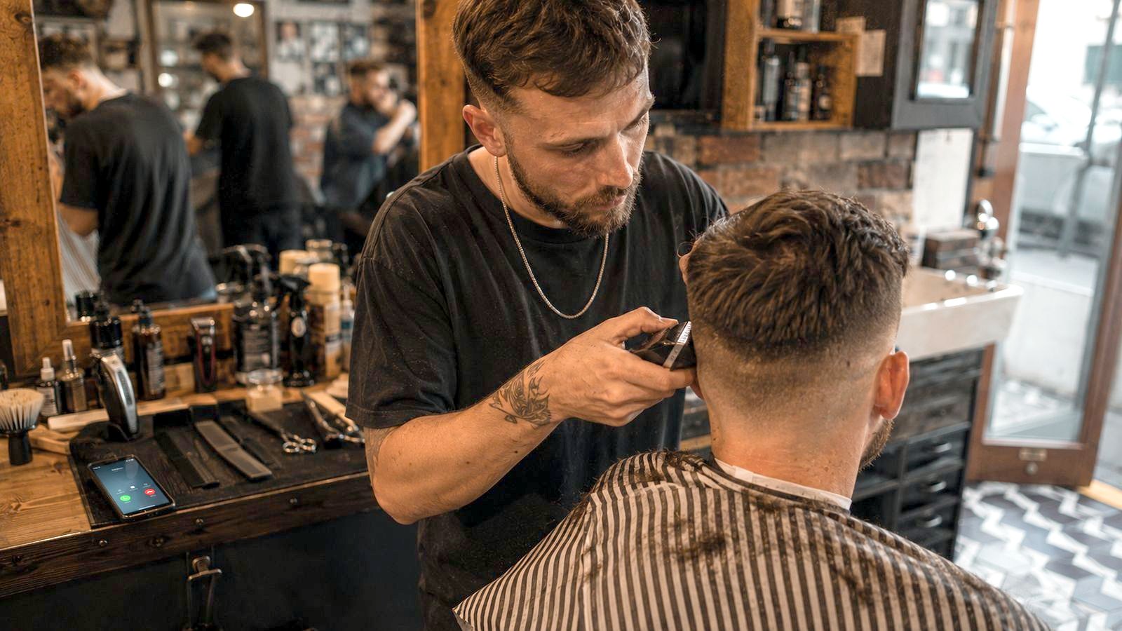 A barber at work, unable to reach a ringing phone.